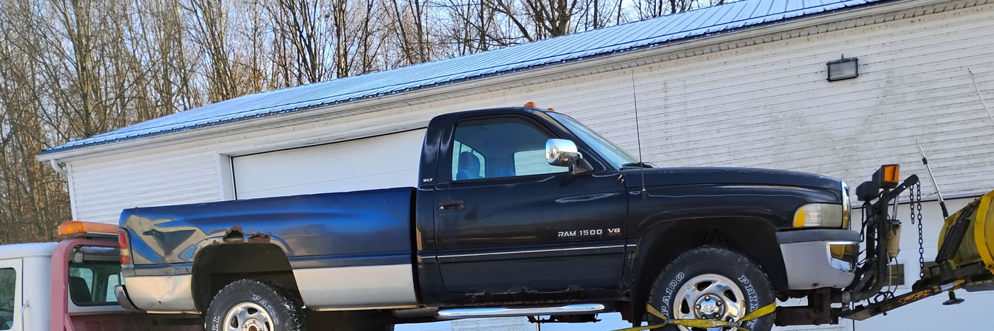 A pickup truck with a snowplow secured on the flatbed in the snow